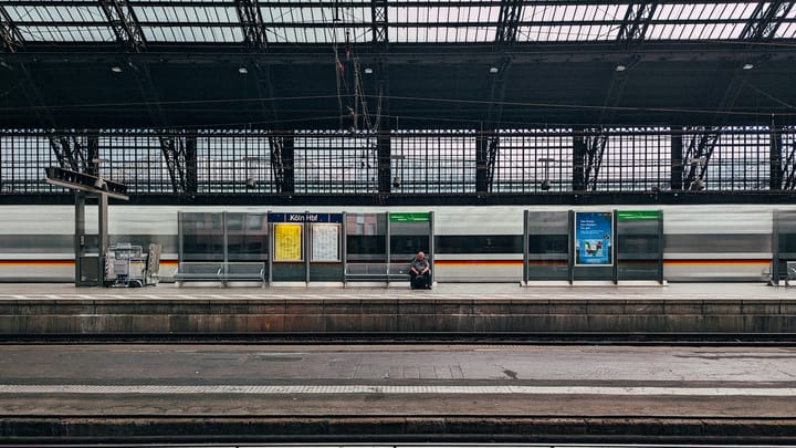 Kölner Hauptbahnhof, ein ICE fährt durch ein Mann sitzt einsam auf der Bank.