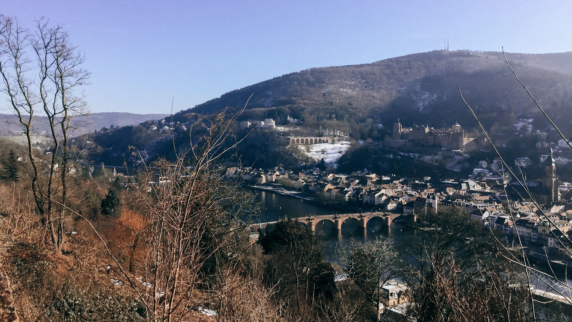 Blick auf Heidelberg mit der Alten Brücke und dem Schloss vom Philosophenweg aus an einem klaren Tag.